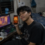 ผู้เล่นเกมสล็อต wink777plus ถือมือถือแสดง Mega Win 18,900 ขณะเล่นผ่านคอมพิวเตอร์