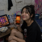 ผู้ใช้งาน wink777plus ถือโทรศัพท์แสดง Mega Win 22,450 พร้อมเกมสล็อตบนหน้าจอคอมพิวเตอร์